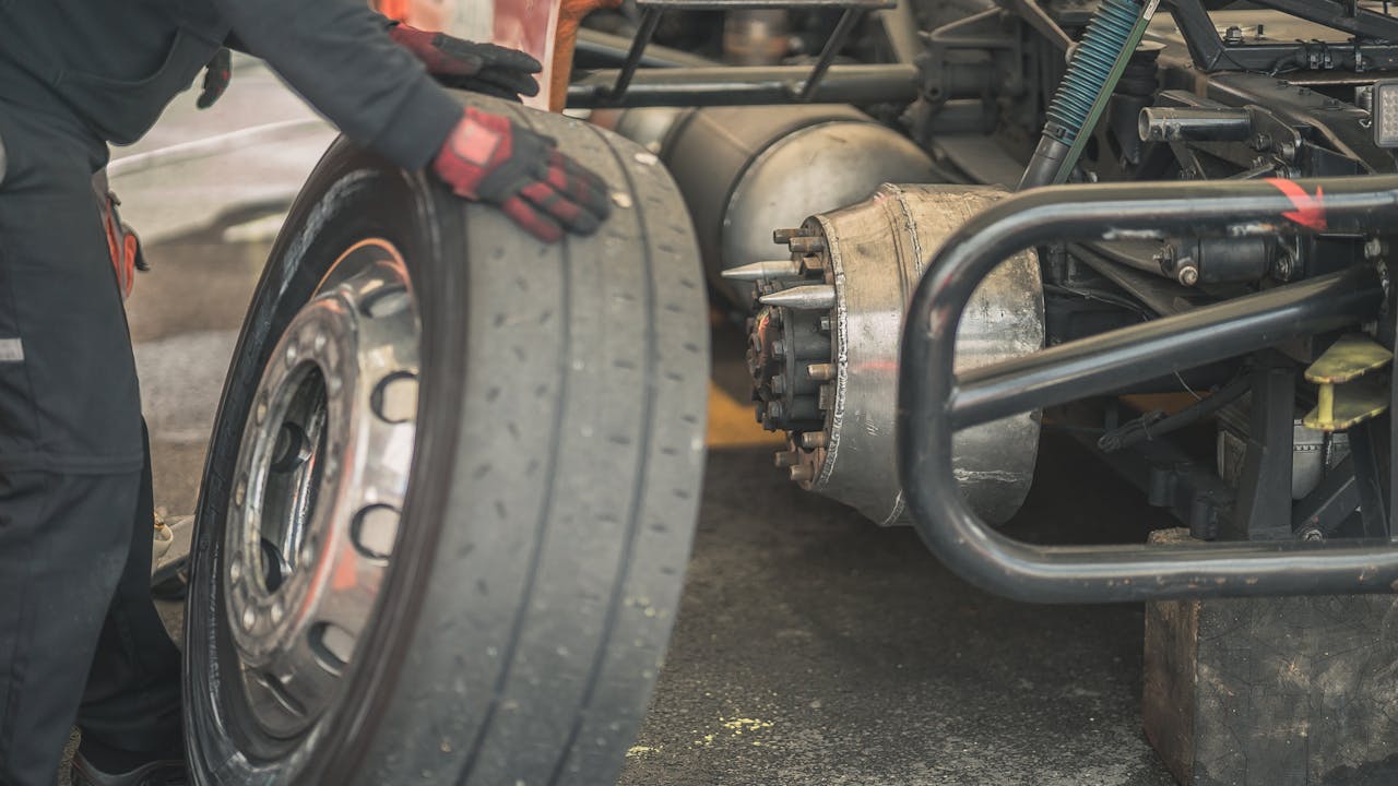 Mechanic working on replacing a tire in a professional automotive garage setting.